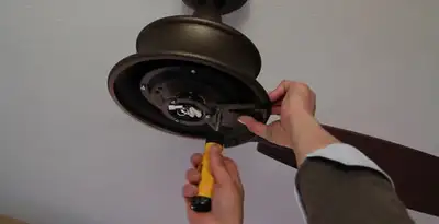 Electrician installing ceiling fan mounting bracket and fixture in Aurora, CO