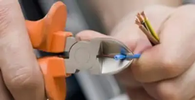 licensed electrician performing precise wire cutting and preparation during electrical service in Aurora, CO