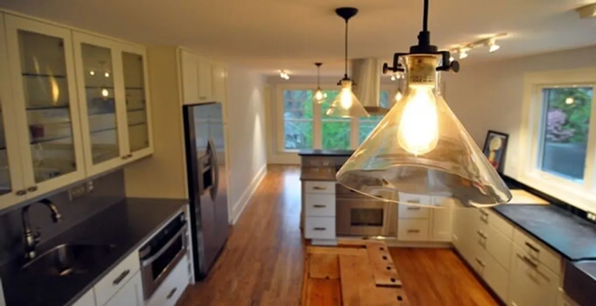 Residential electrician installing modern indoor light fixture in a home in Aurora, CO