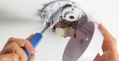 Certified technician wiring smoke detector during installation in Aurora, CO